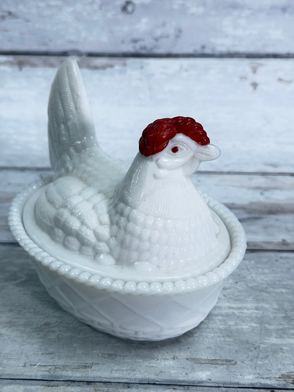 Milk glass hen covered dish with red comb, resting in a beaded nest tray