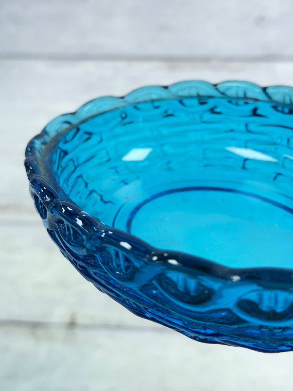 Blue glass covered candy dish with scalloped rim, side view