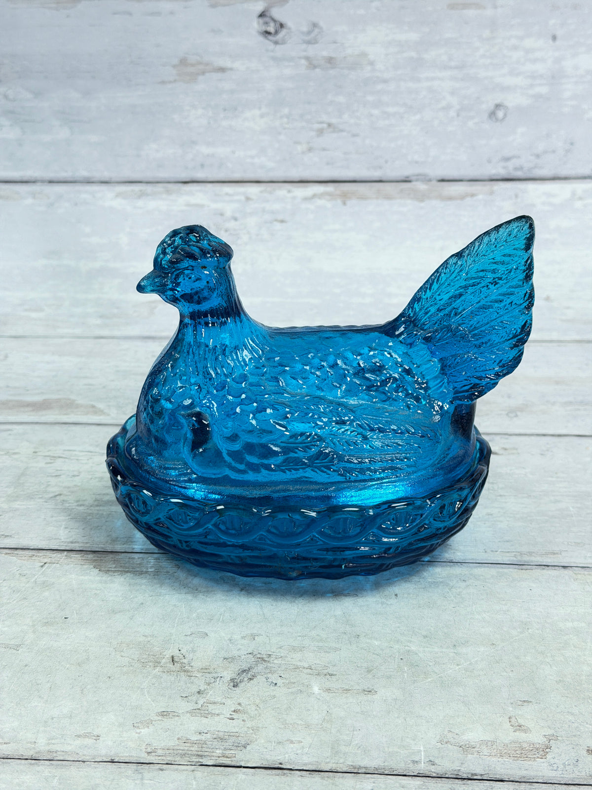 Blue glass hen on nest covered candy dish, profile view