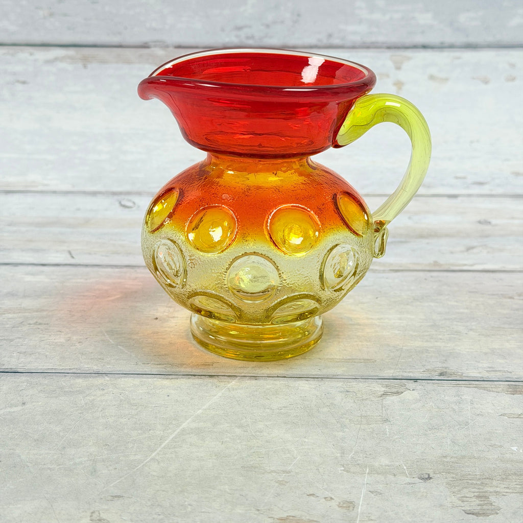 Reverse of amberina thumbprint glass pitcher showing applied handle and ring foot