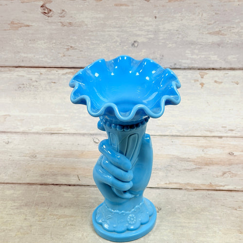 Angled view of blue hand-and-cornucopia vase showing flared opening