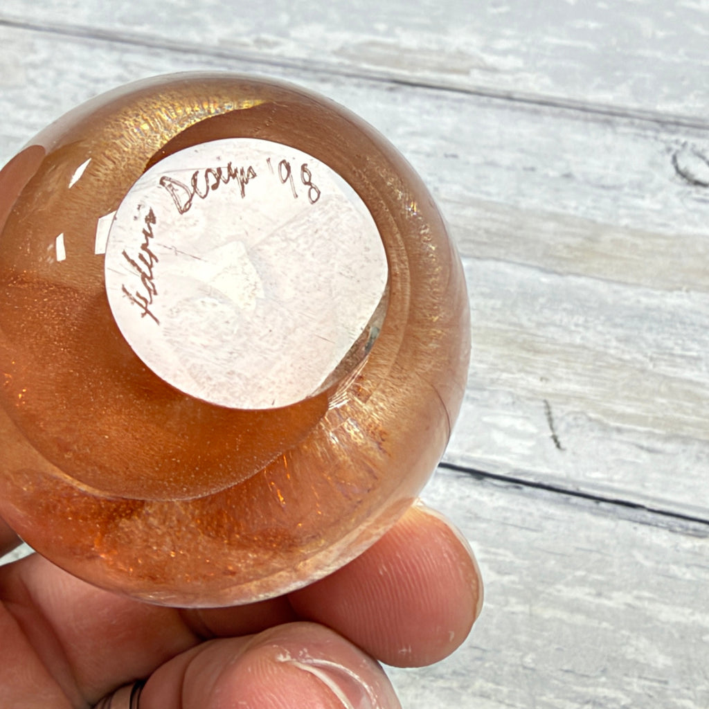 Polished underside of the glass paperweight showing an engraved signature, 98 date and fine surface scratches