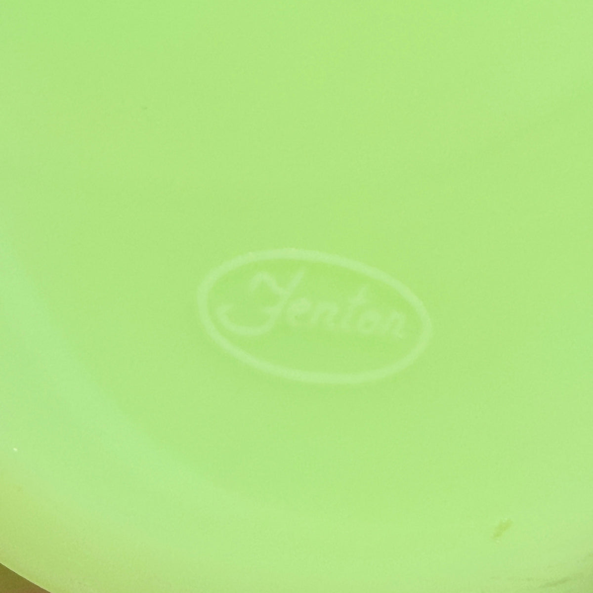Close-up of molded oval Fenton maker mark on satin glass jar