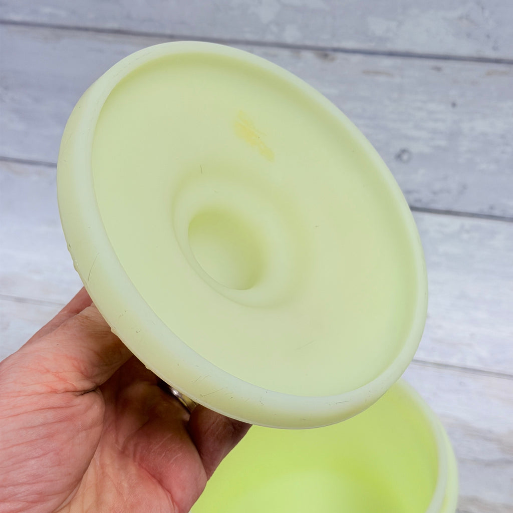 Underside of custard satin glass jar lid showing surface marks and a small discolored spot