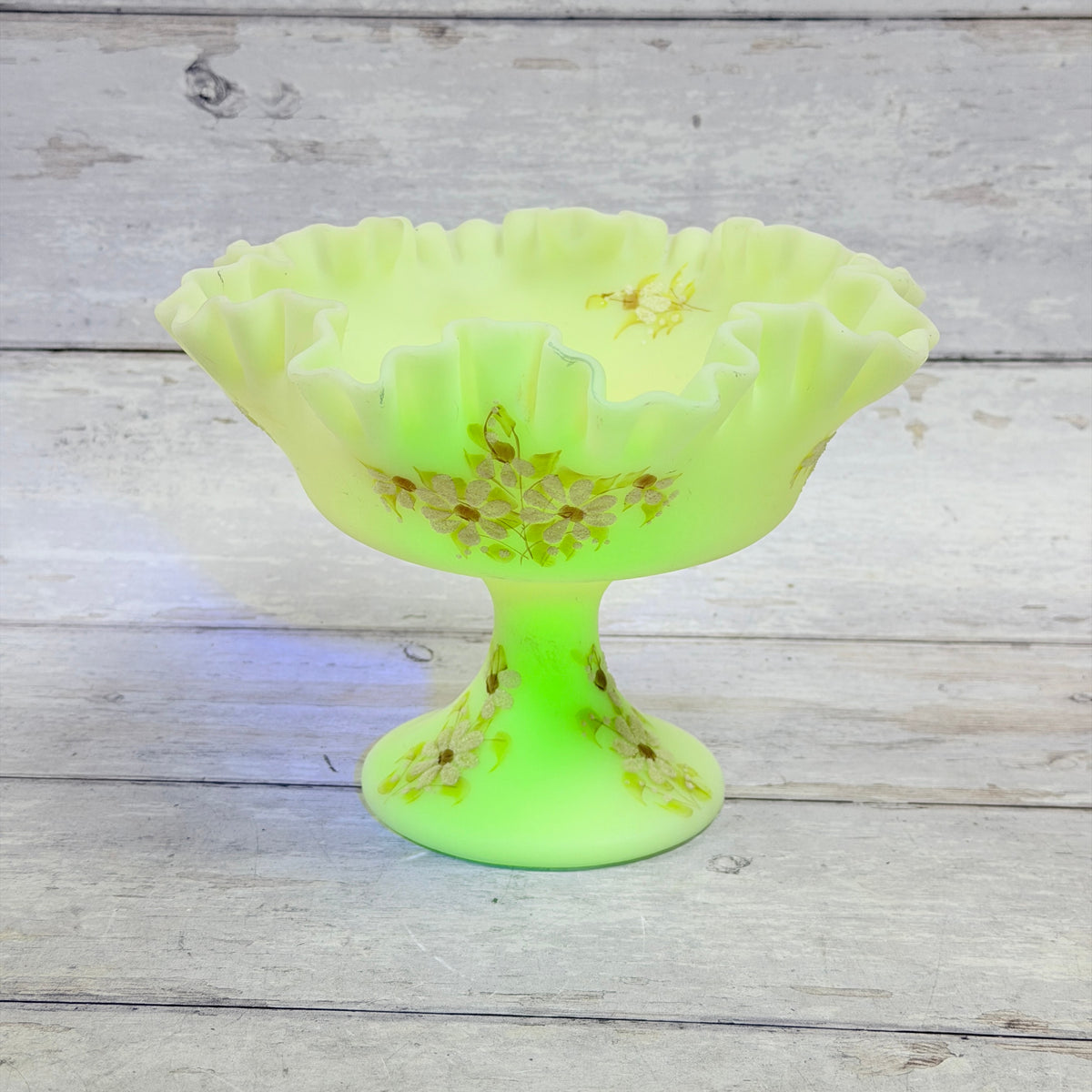 Underside of Fenton custard glass compote showing the molded oval maker mark and painted artist signature