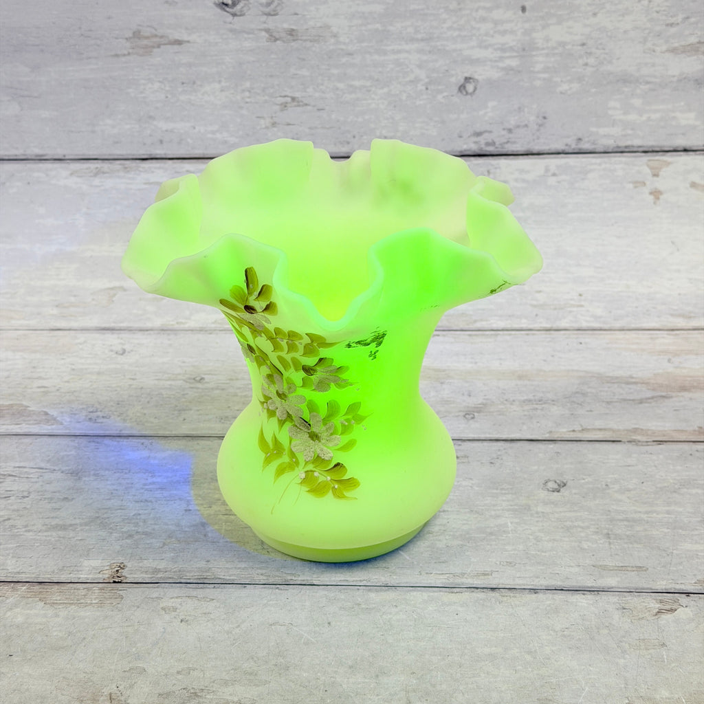 Ruffled rim and interior of Fenton custard uranium glass daisy vase under UV light