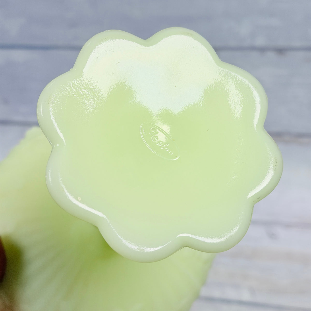 Scalloped underside of custard glass compote showing the molded oval Fenton mark and light base wear