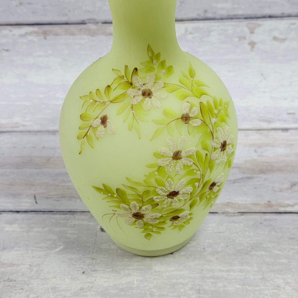Close-up of hand-painted textured white daisies, brown centers and green leaves on Fenton custard satin glass vase