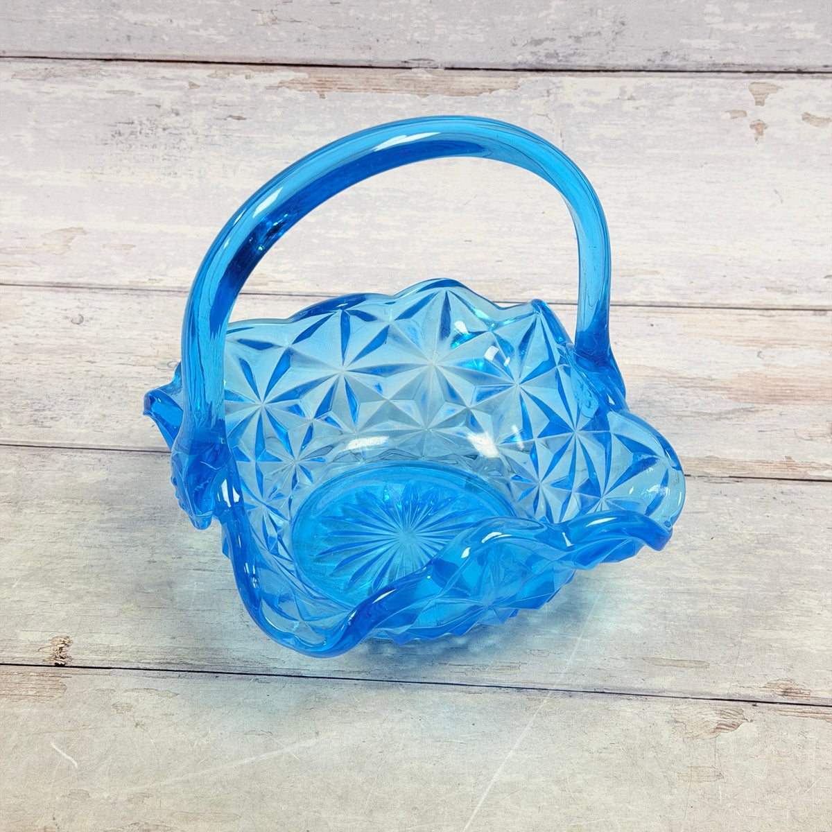 Angled view into blue glass basket with ruffled rim and patterned base