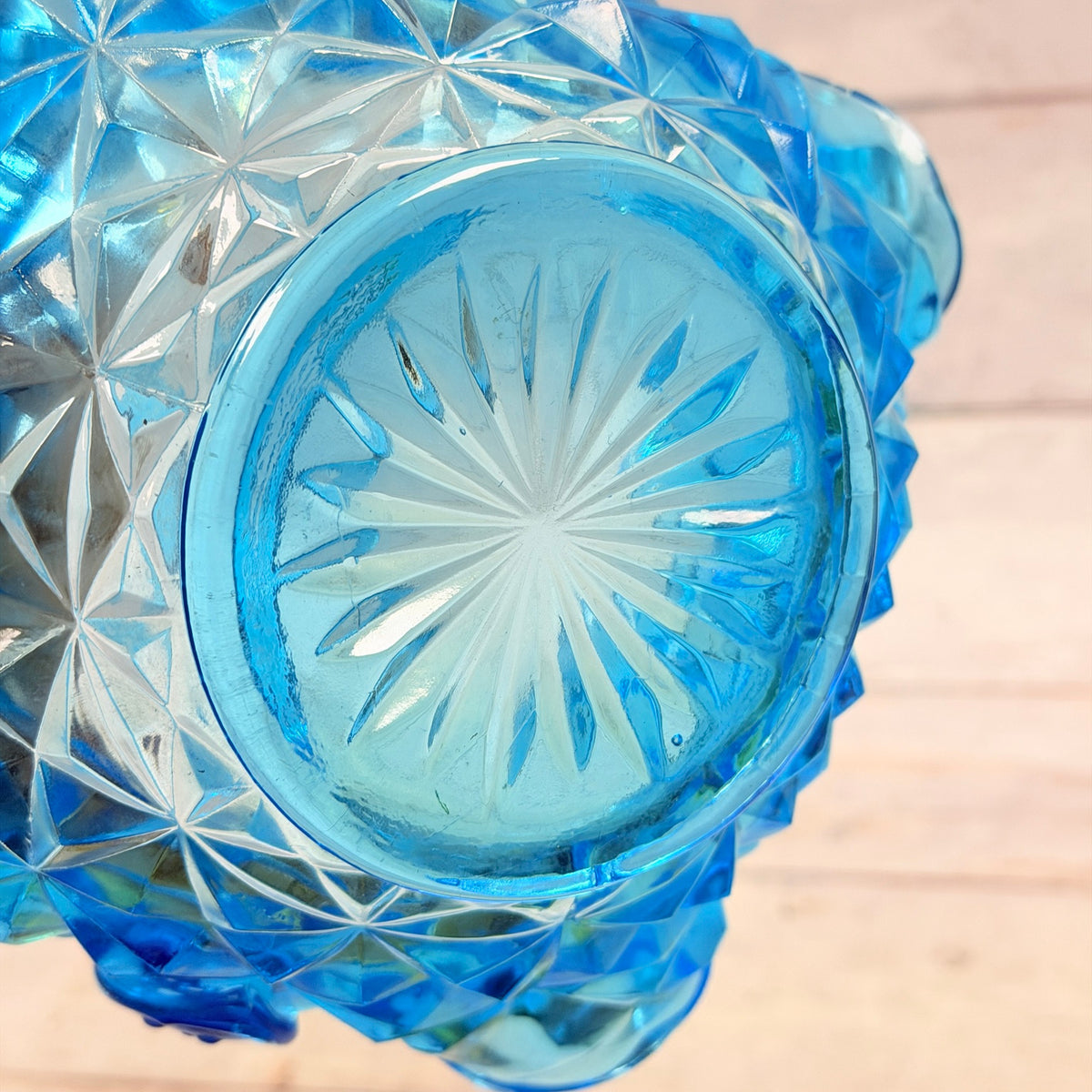 Underside of blue glass basket showing starburst base and surface wear