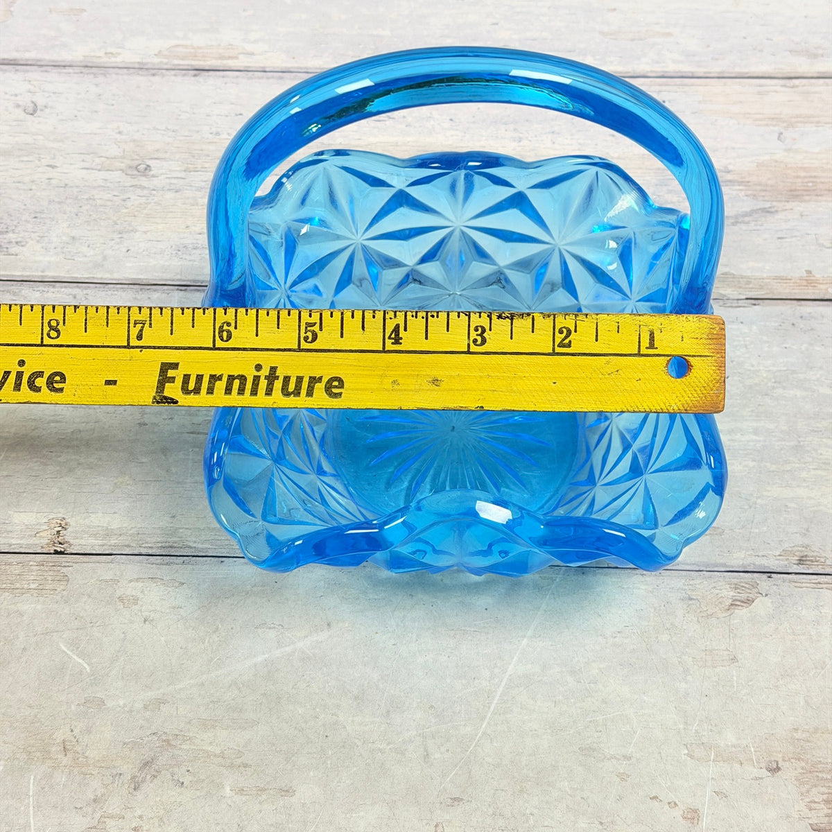 Blue glass handled basket beside horizontal ruler