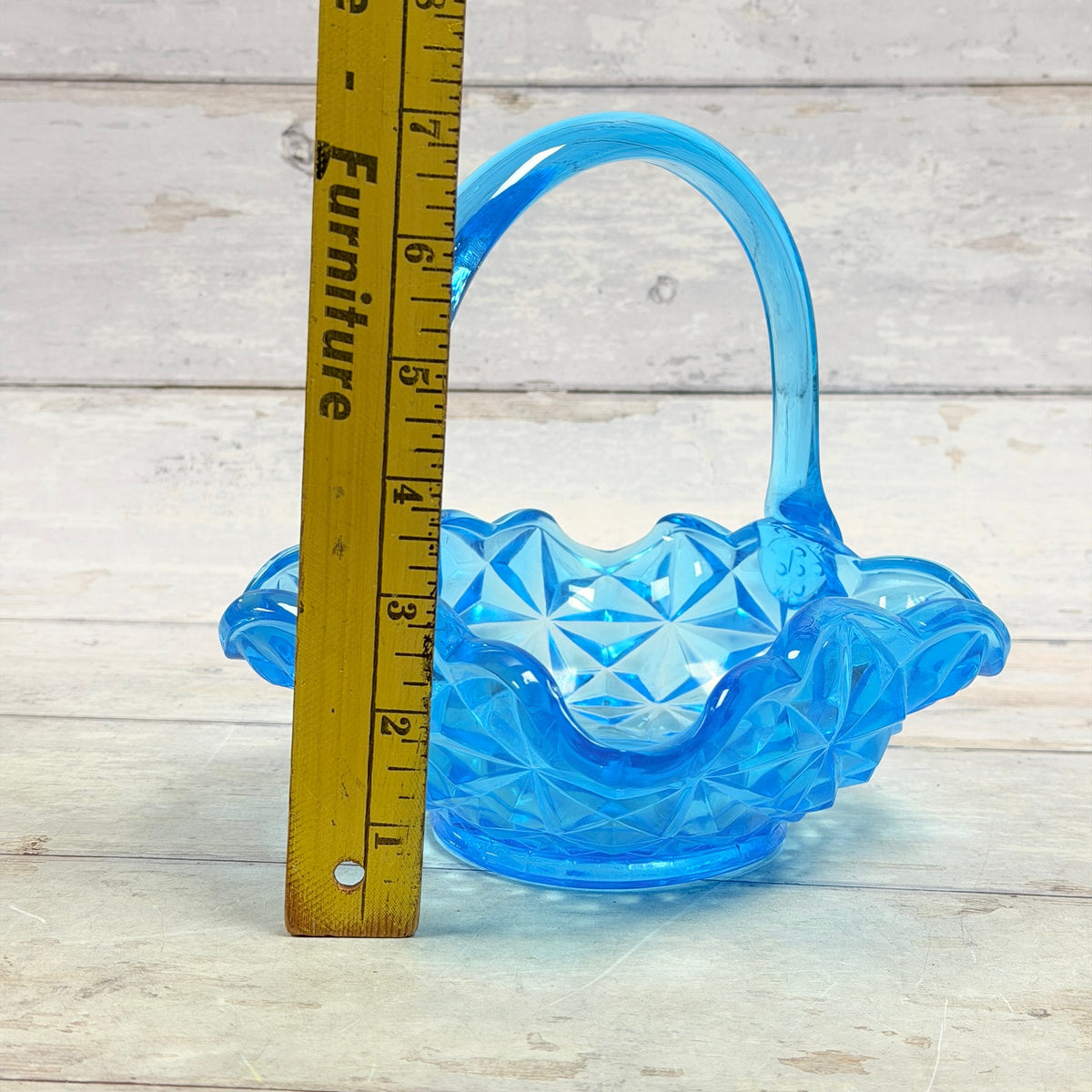 Blue glass basket beside vertical ruler showing approximate seven-inch height