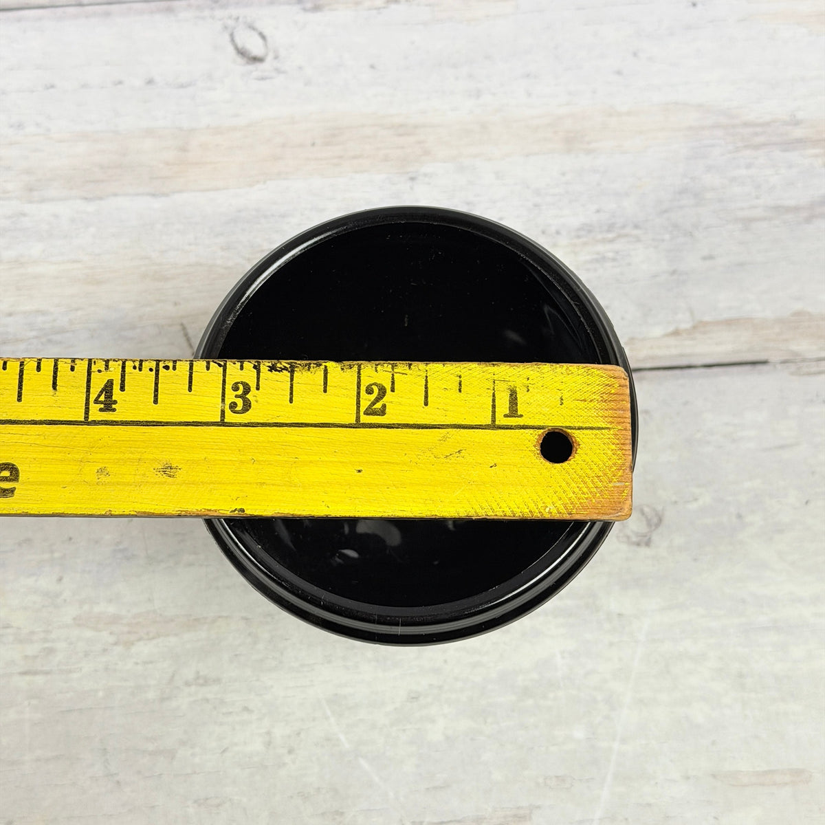 Black amethyst bird bowl with ruler across opening showing approximately three and one-quarter inches wide