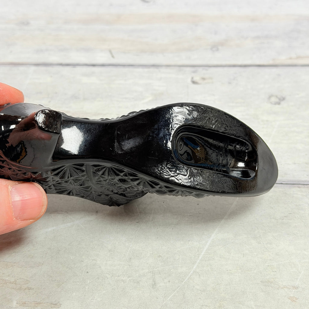 Underside of black amethyst glass shoe showing heel and base surface wear