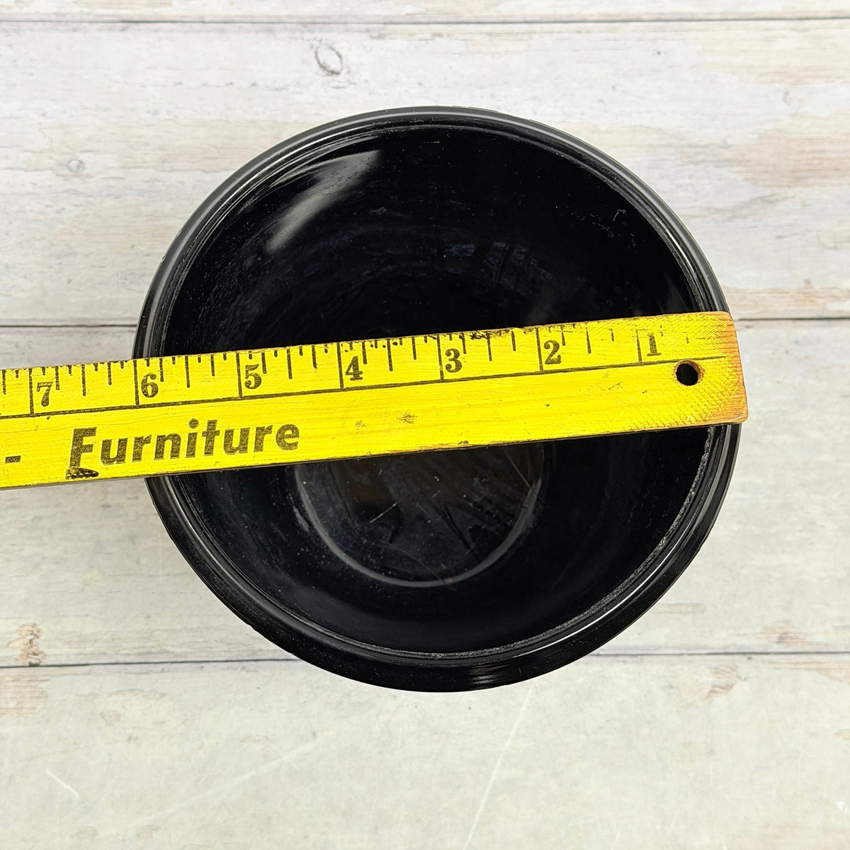 Black amethyst footed fern bowl with ruler across the opening showing approximately six-inch diameter