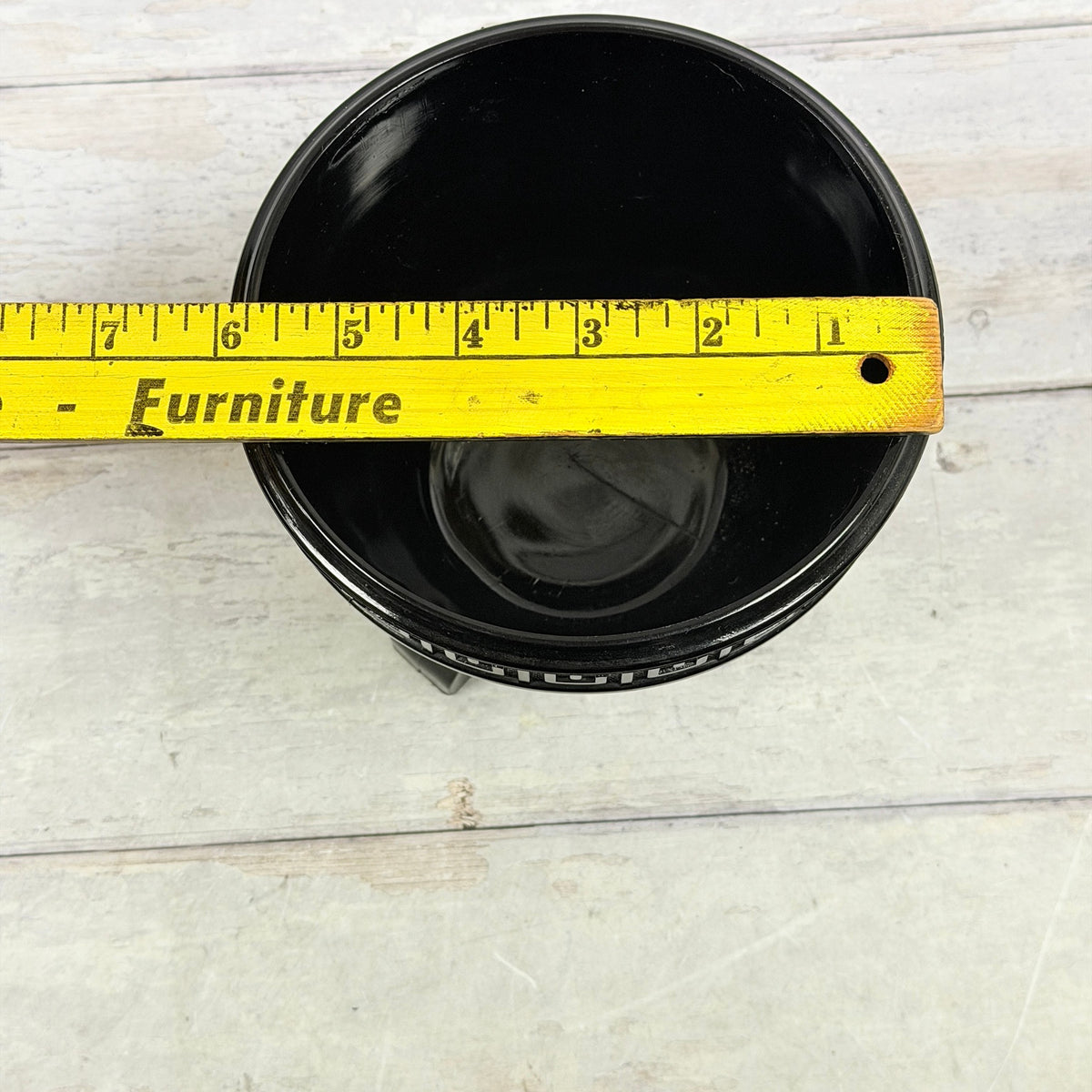 Black amethyst footed fern bowl with ruler across the opening showing approximately six-inch diameter