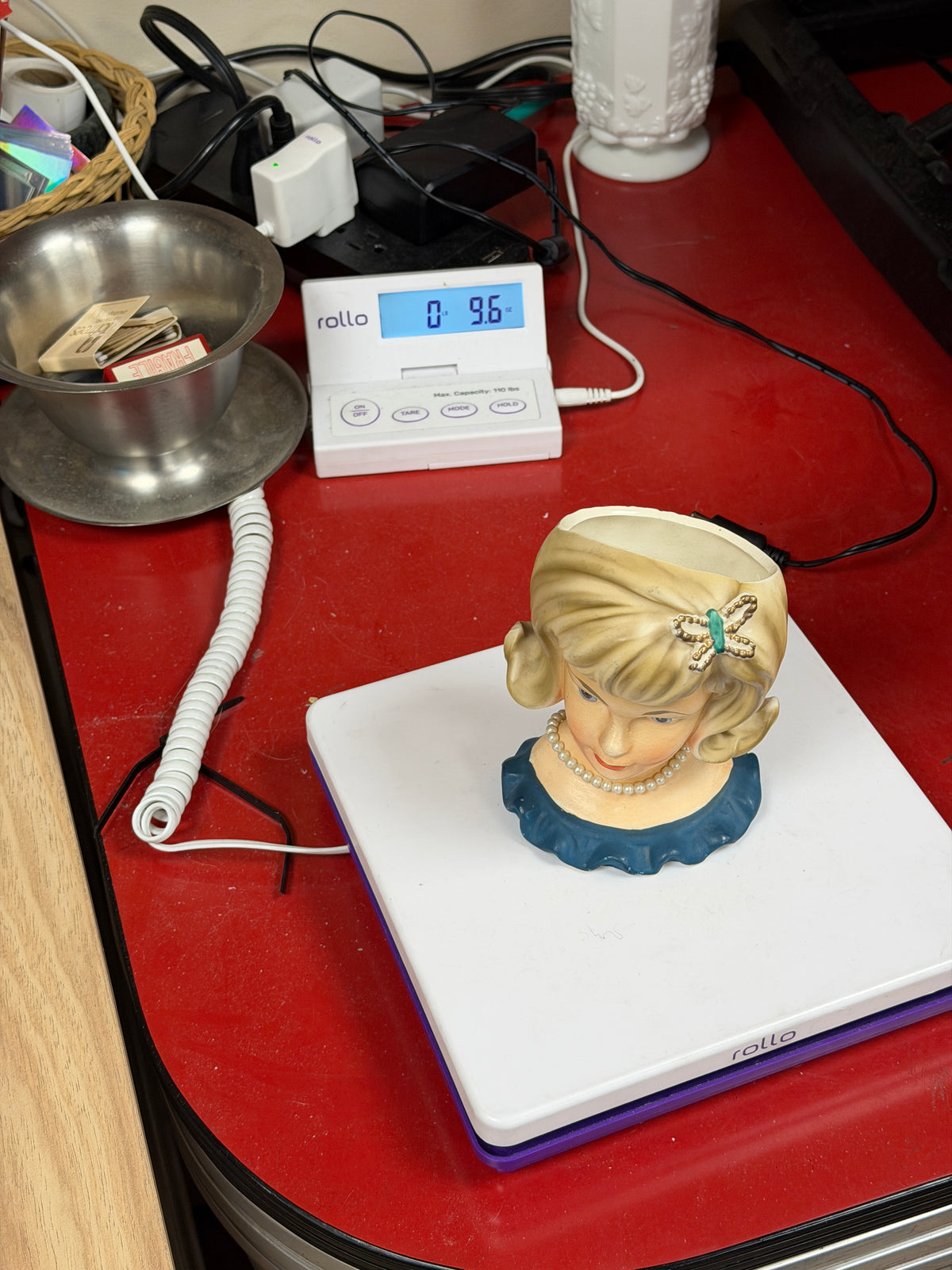 Lady head vase on scale with displayed item weight