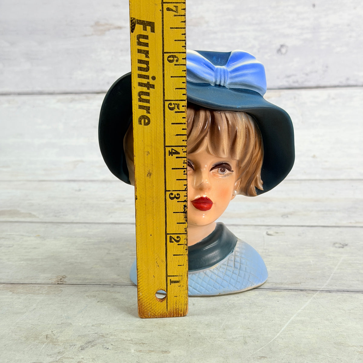 Blue hat head vase beside height ruler