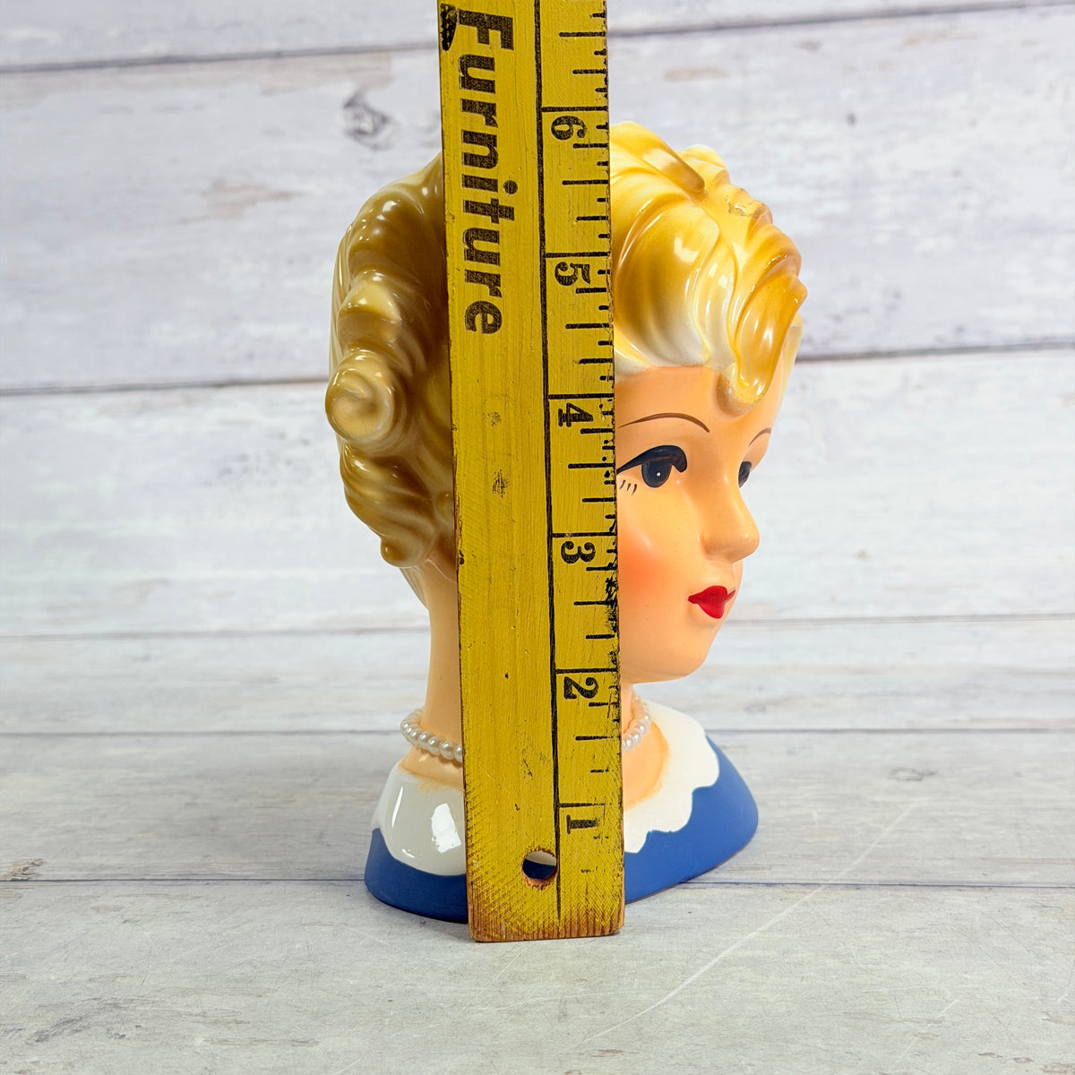 lady head vase beside height ruler