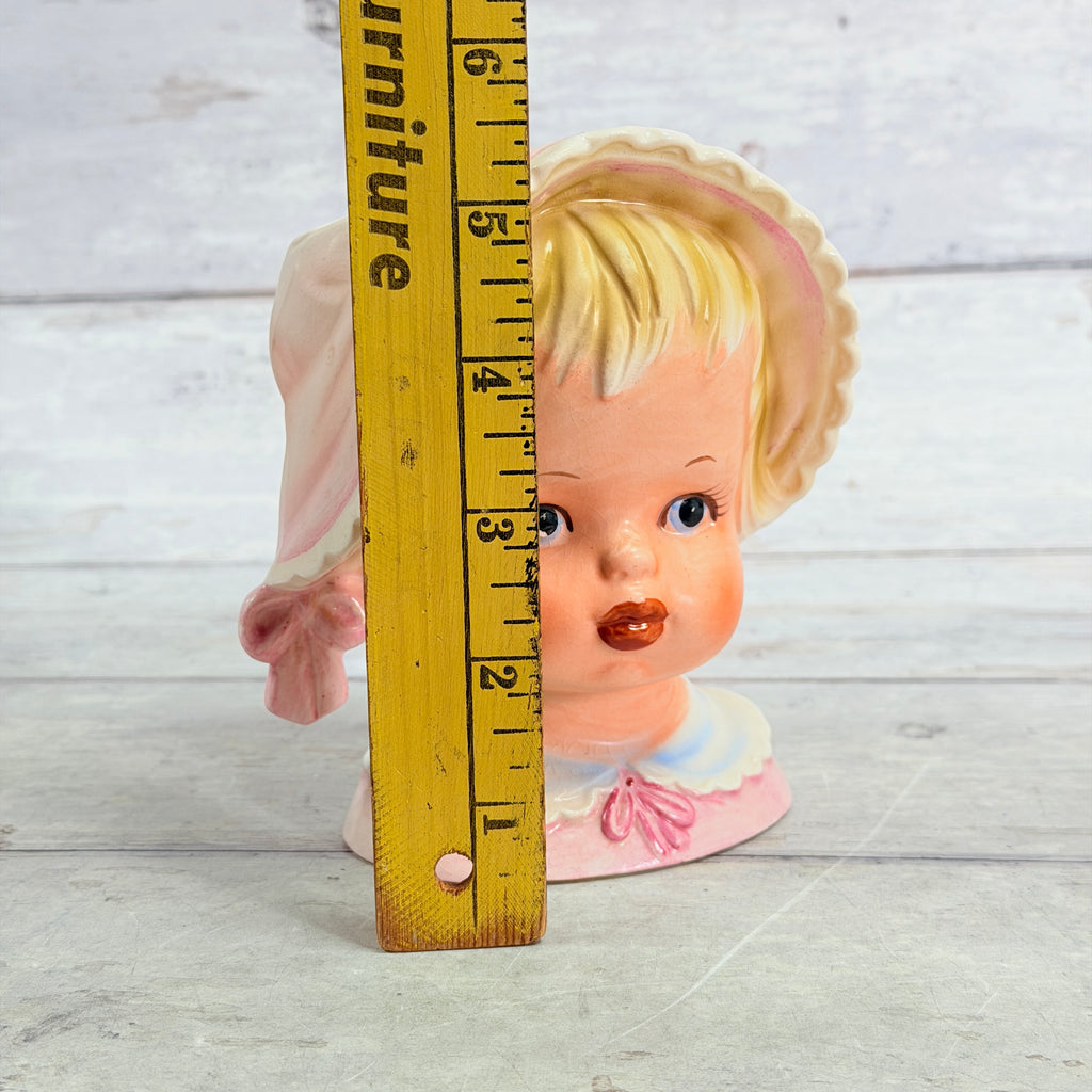 Pink bonnet vase beside height ruler