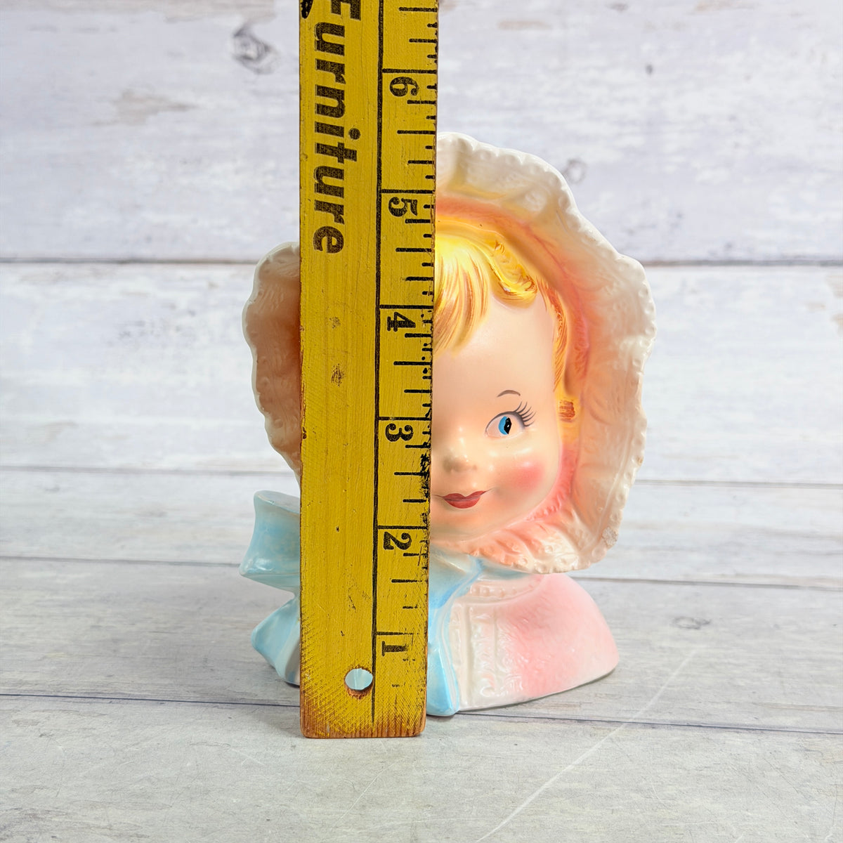 Pink bonnet child vase beside height ruler