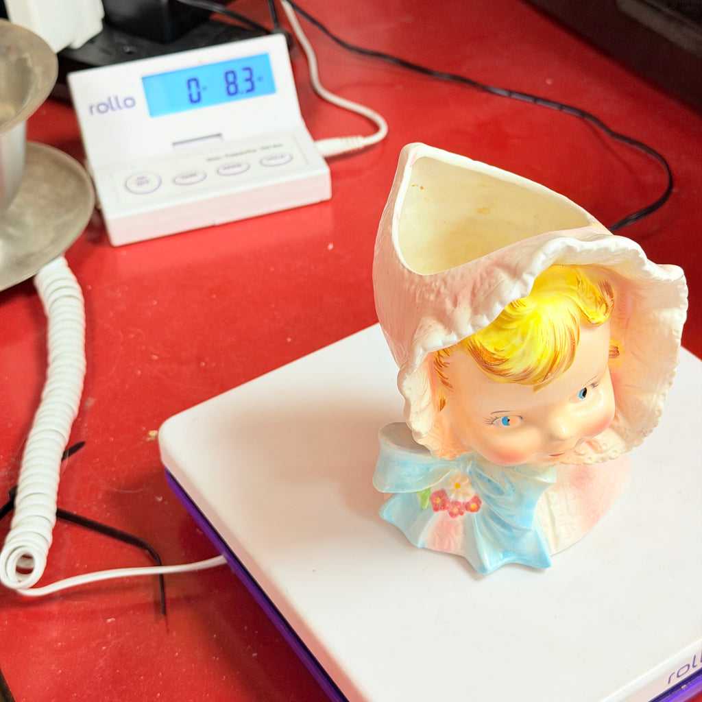 Pink bonnet child vase on scale