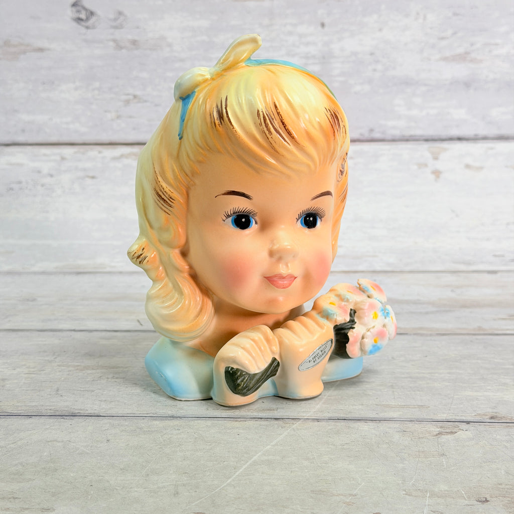 Front showing blonde girl, blue bow and flower bouquet