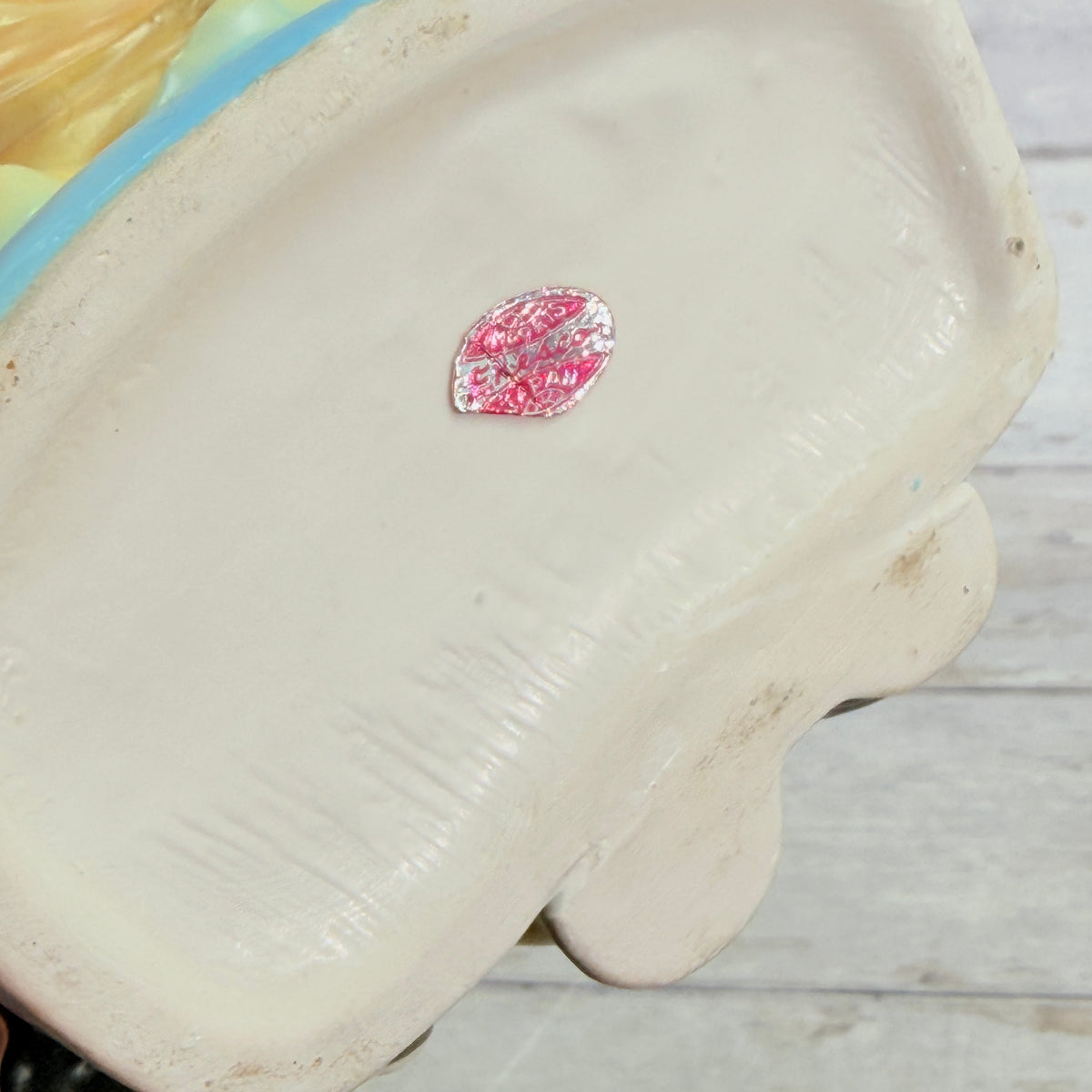 Worn foil label on girl vase base