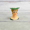 Front of small green hat head vase with pearl-style jewelry