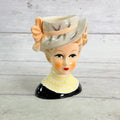 Front of gray hat vase with peach bow and yellow collar