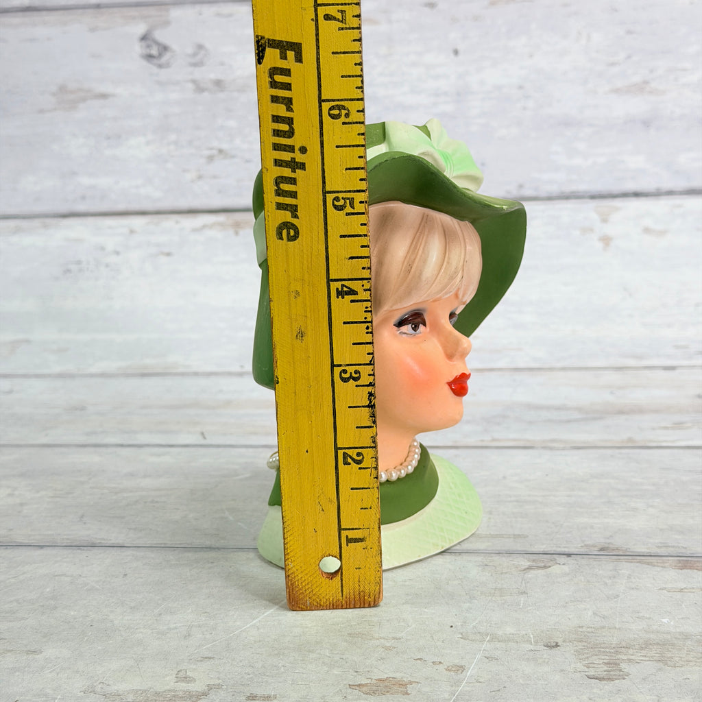 Green hat vase beside ruler