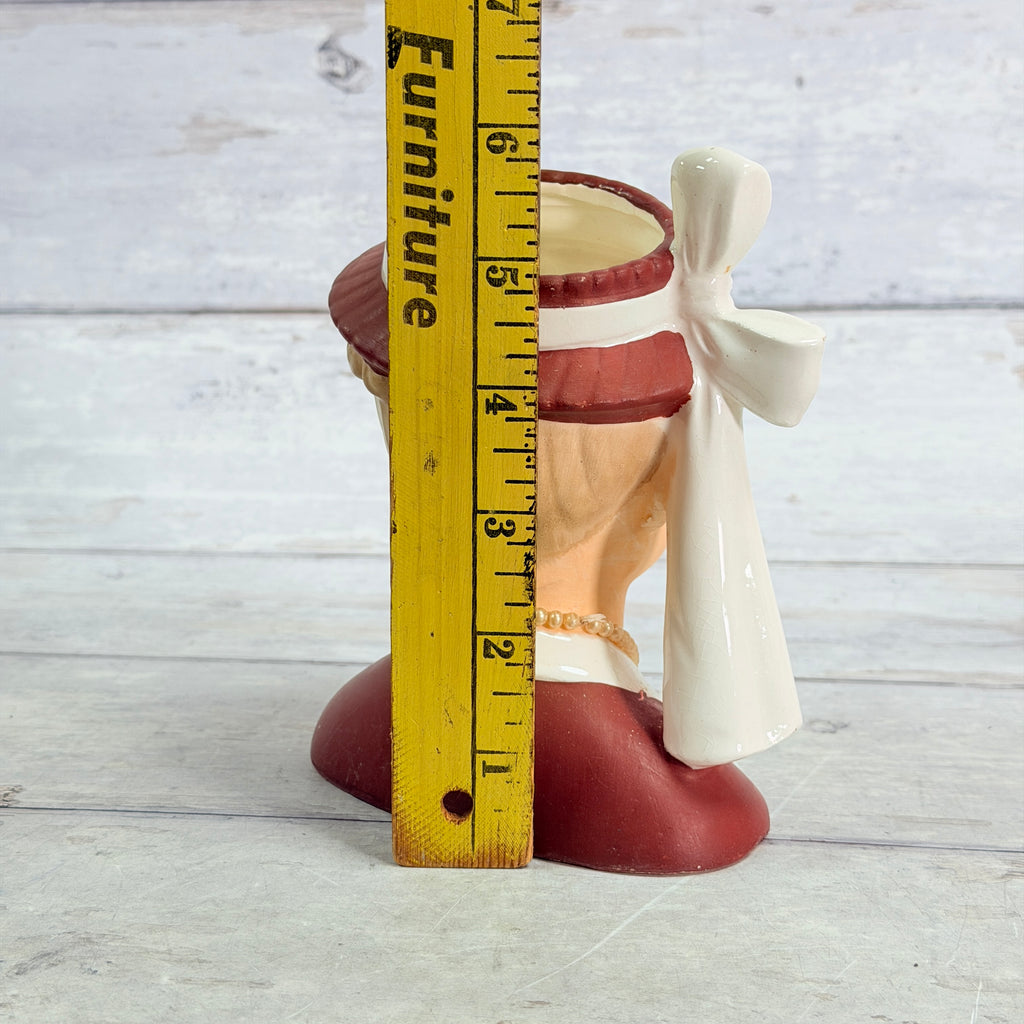 Burgundy hat vase beside ruler