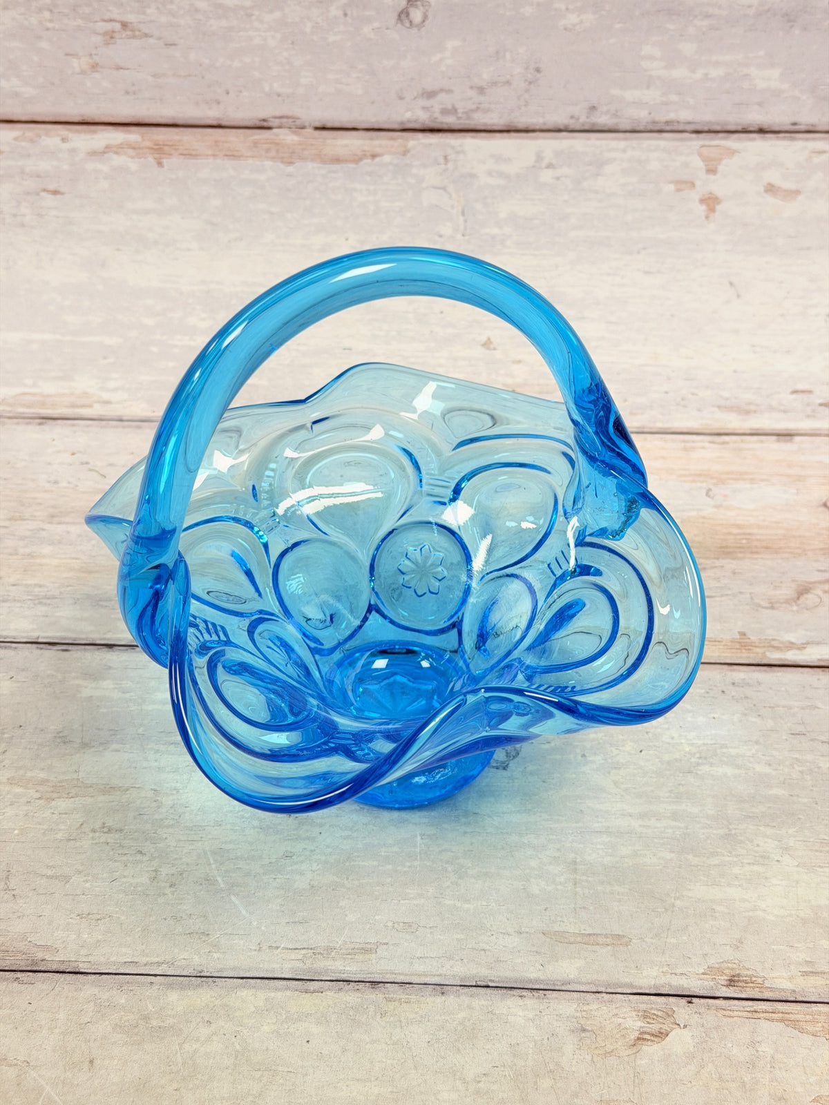 Angled view of Moon and Star pressed glass basket with crimped rim