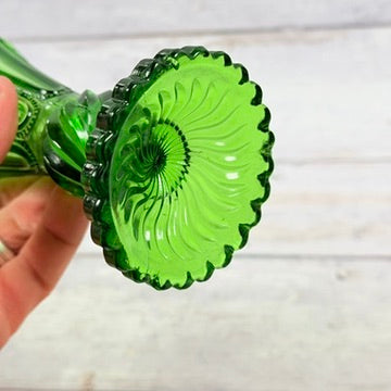 Underside of emerald green pressed glass vase with swirling foot motif