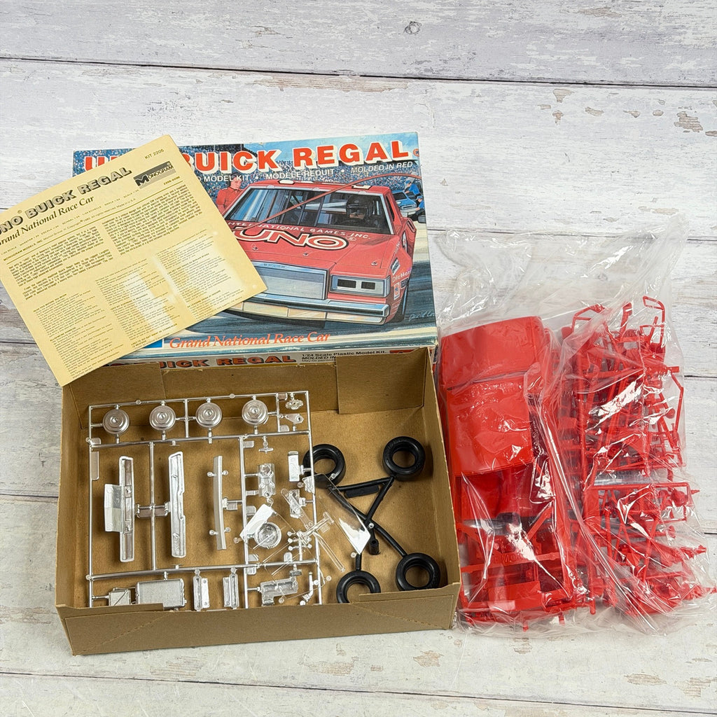 Open Monogram UNO Buick Regal kit with red parts, chrome and clear sprues, tires and instructions