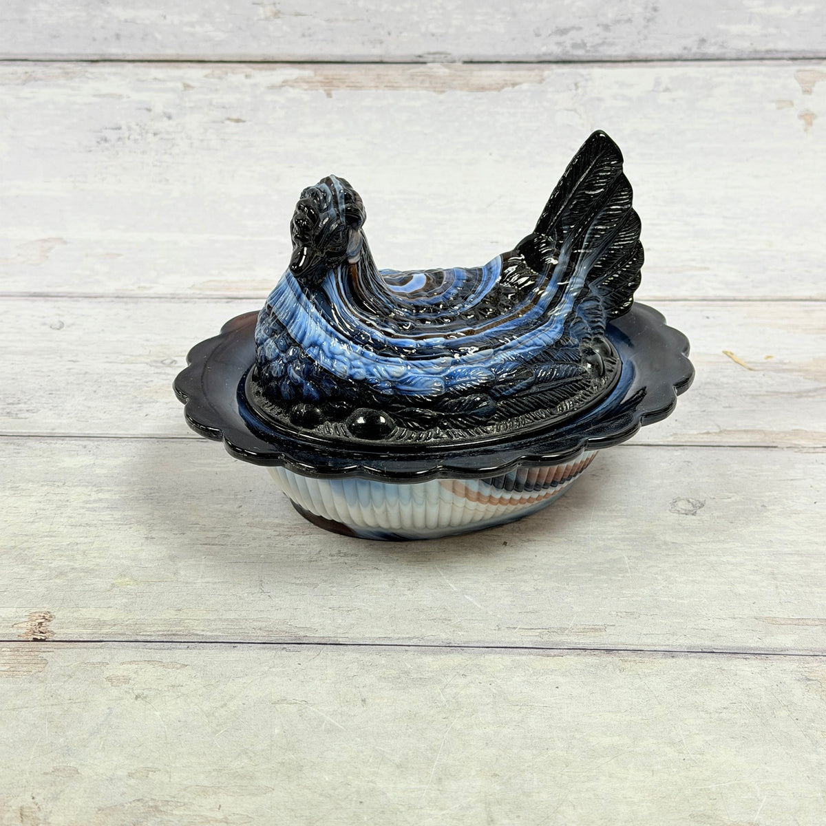 Side view of Mosser Glass amethyst and white slag glass hen-on-nest dish
