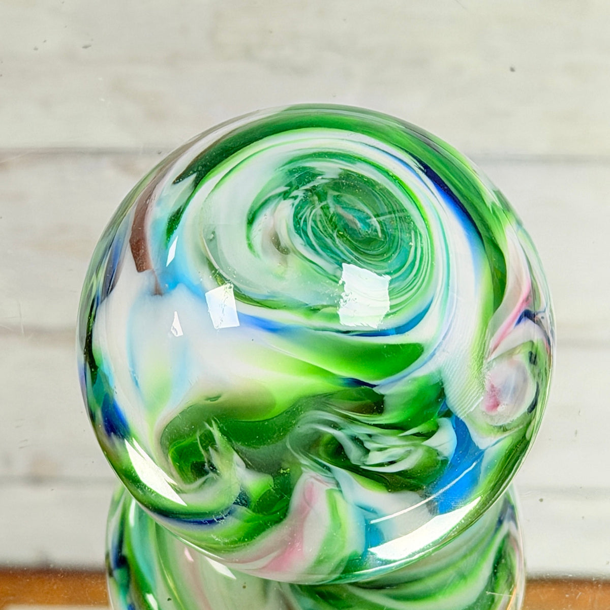 Close view of colorful swirling ribbons inside round glass paperweight