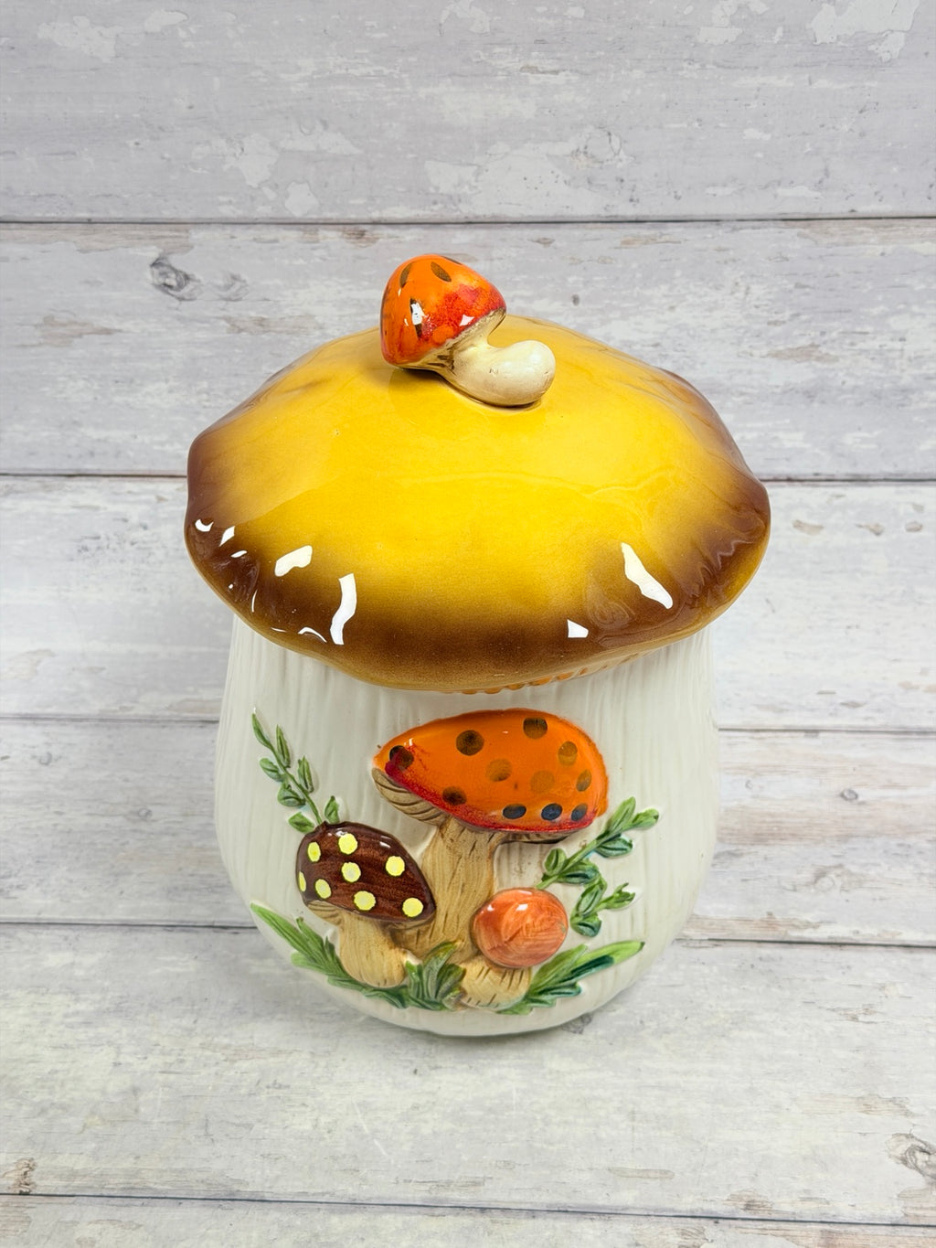 Alternate front view of ceramic mushroom canister showing its glossy yellow-brown lid and raised mushroom detail