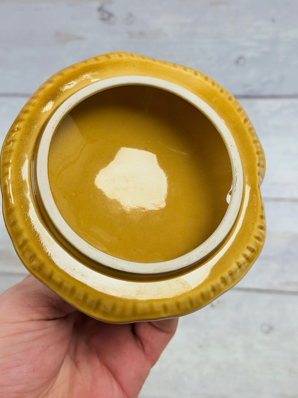 Angled view of glossy gold-brown lid and mushroom finial