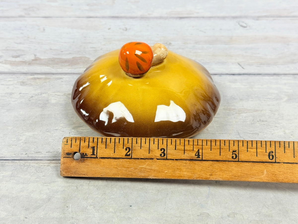 Gold and brown Merry Mushroom ceramic lid with orange mushroom finial