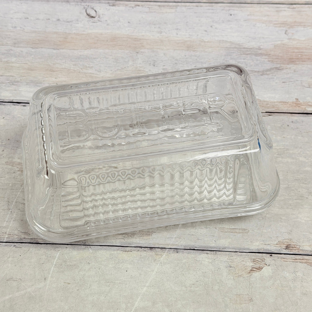 Clear glass butter dish showing embossed BUTTER lettering across the lid