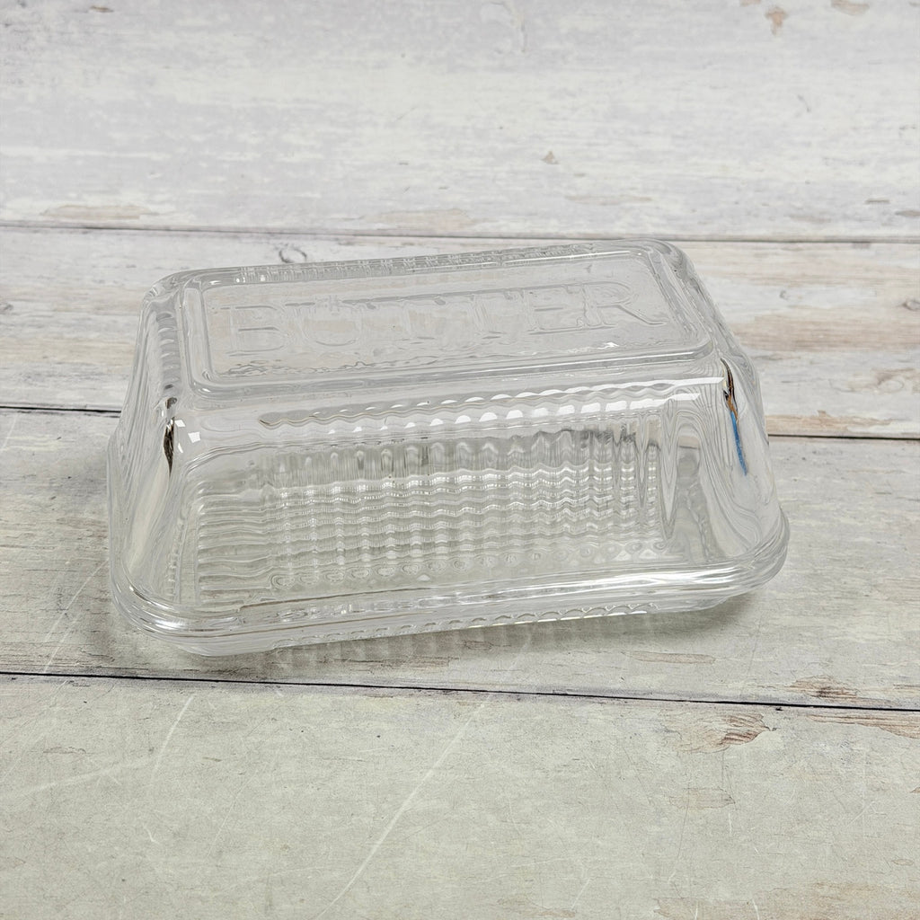 Clear ribbed glass butter dish with embossed BUTTER lid, front view