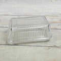 Clear ribbed glass butter dish with embossed BUTTER lid, front view