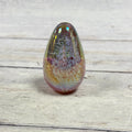Glass Eye Studio pink and lavender iridescent egg paperweight with a white feather-like pattern