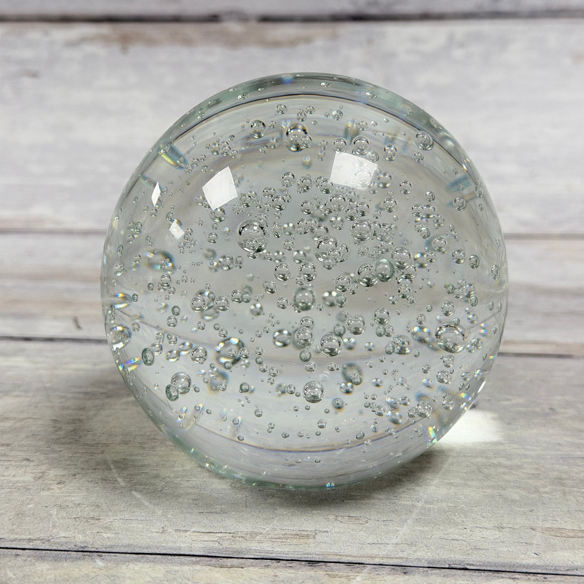 Clear round bubble glass paperweight with suspended air bubbles, front view
