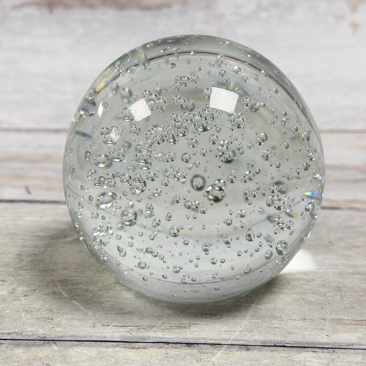 Clear bubble art glass paperweight showing rounded form and varied internal bubbles