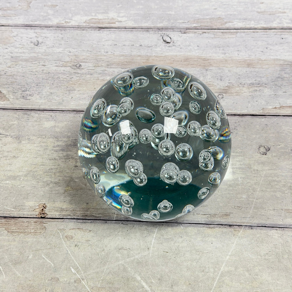 Oversized clear glass paperweight showing suspended bubbles and subtle aqua tint