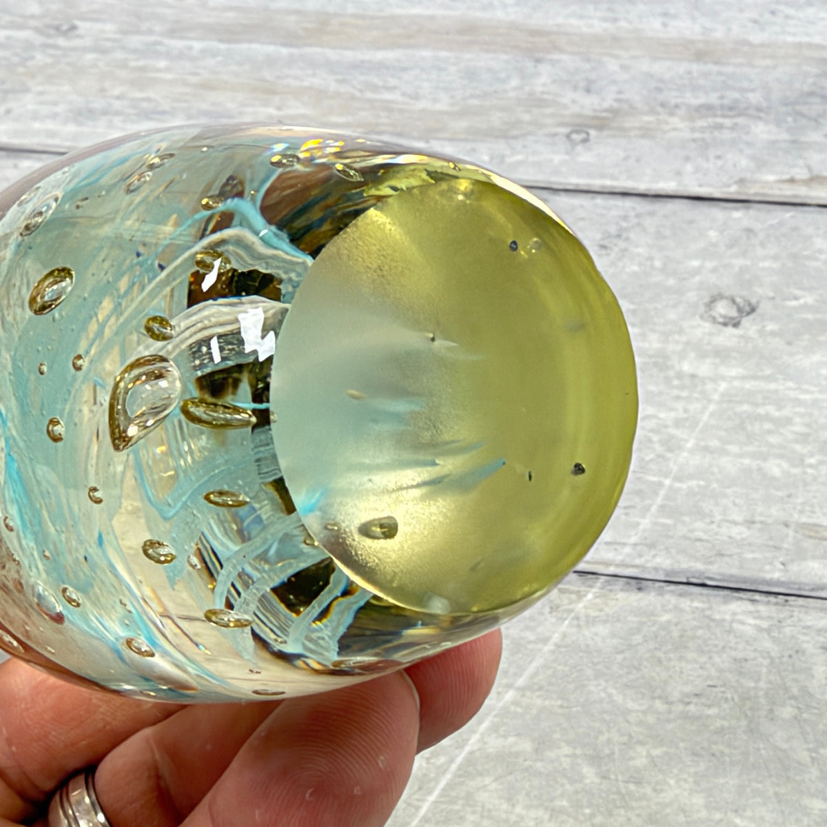 Ground flat underside of unmarked blue jellyfish glass paperweight showing small specks and base wear