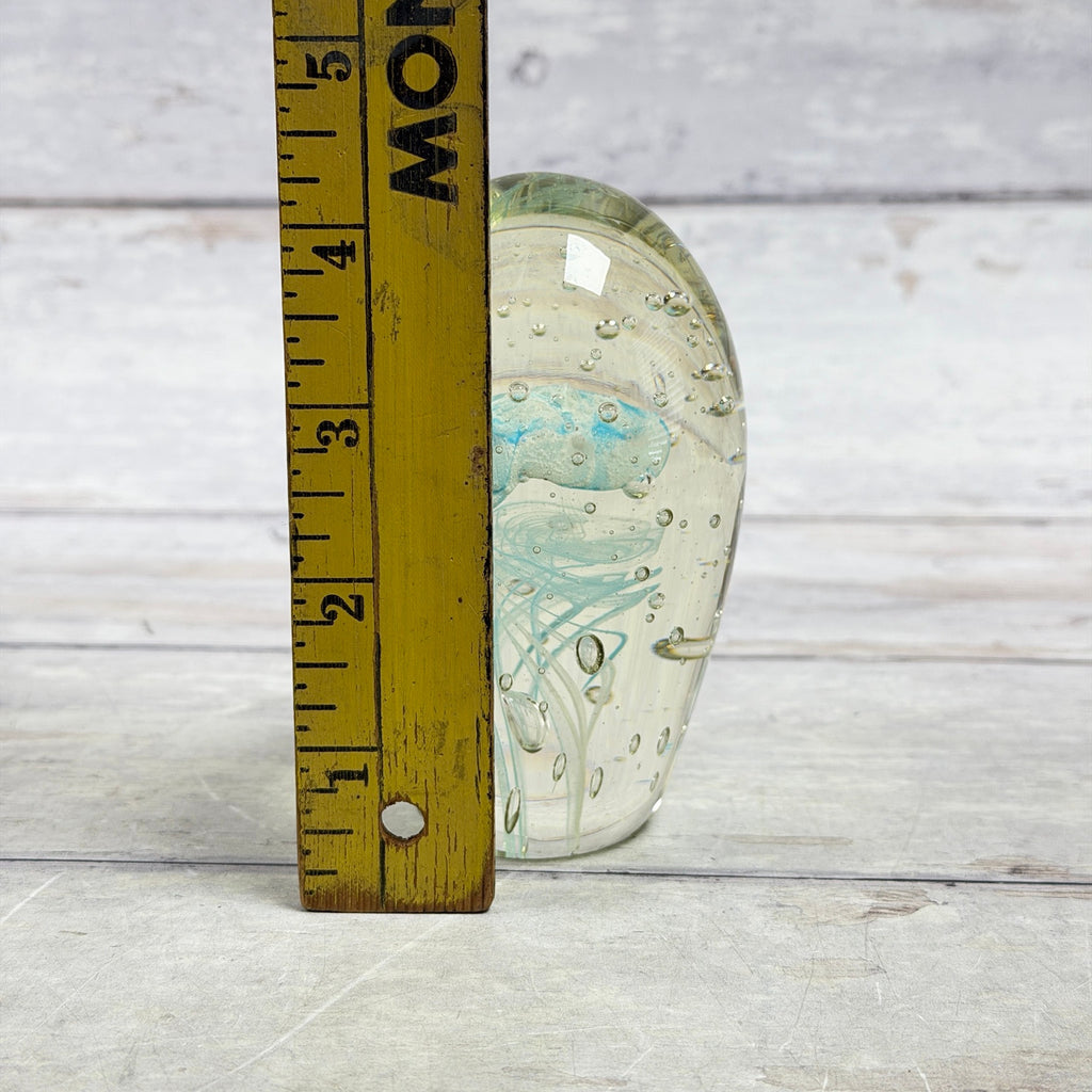 Blue jellyfish glass paperweight beside a wooden ruler showing its approximate four-inch height