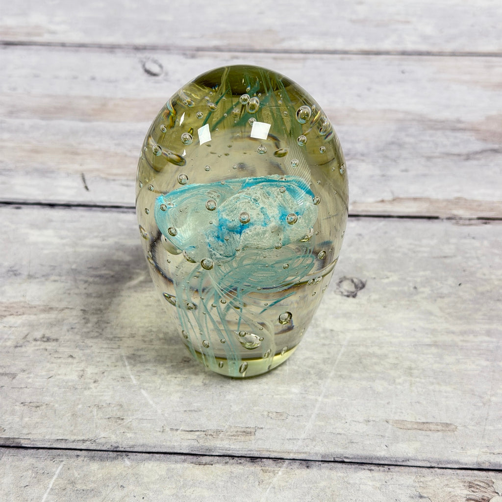 Reverse view of blue jellyfish glass paperweight showing pale blue trailing strands and air bubbles
